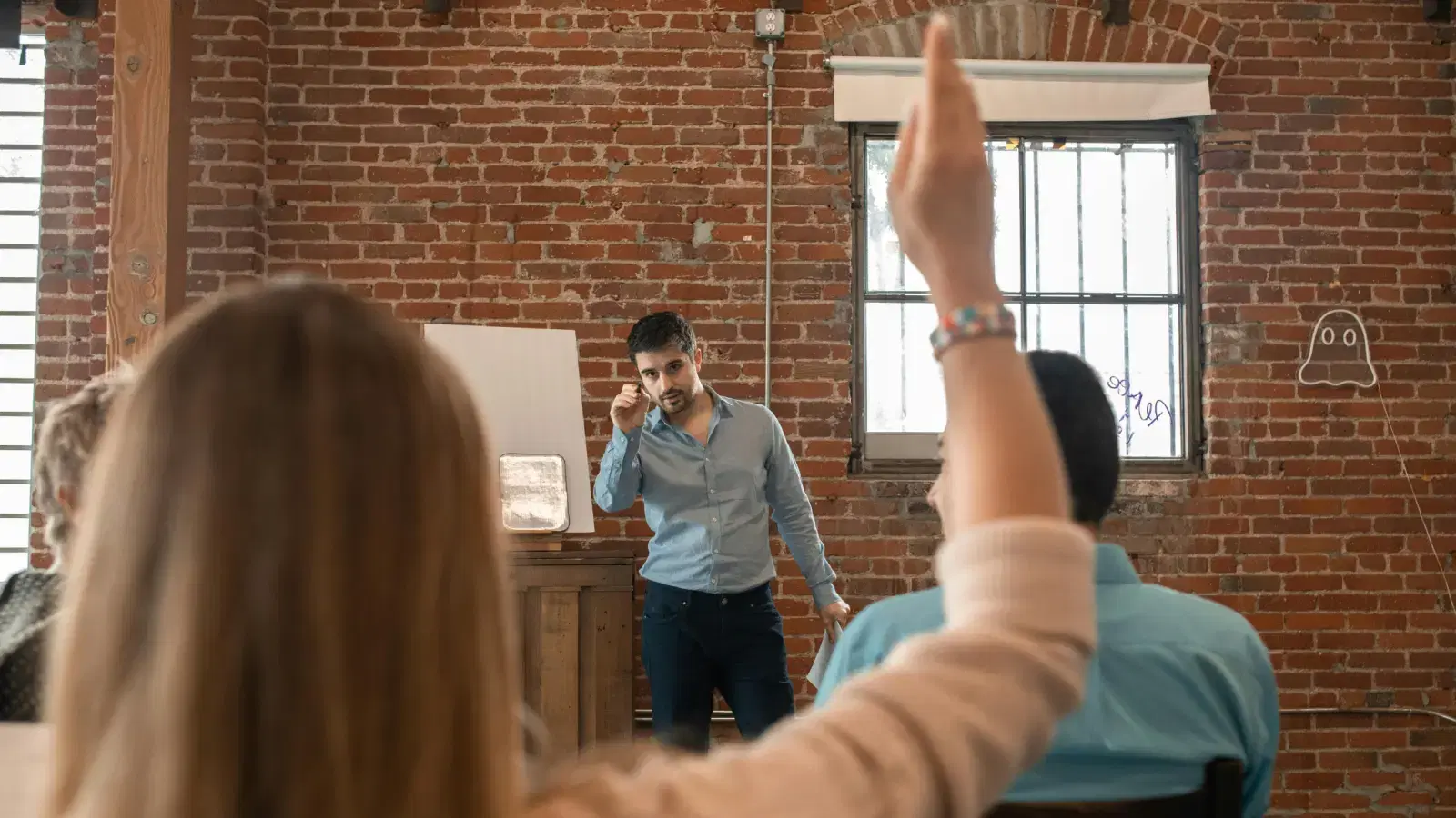 An audience member raising a hand to ask a question during a talk