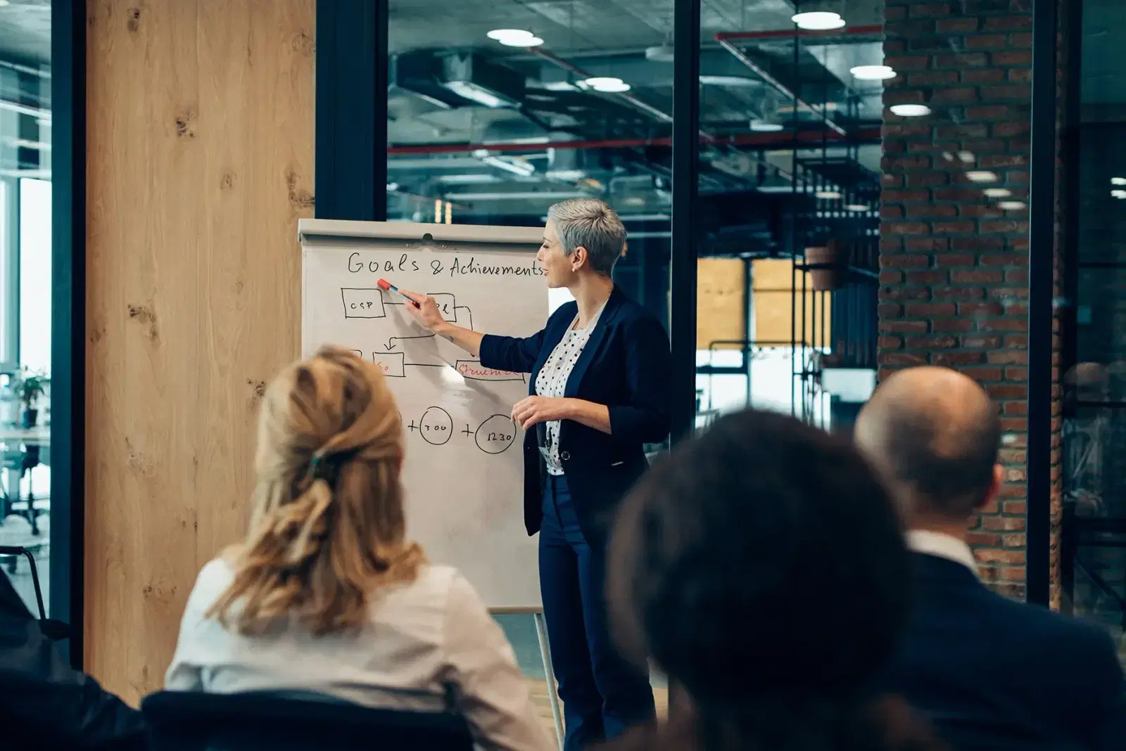 A presenter pointing to a chart on a board while explaining it