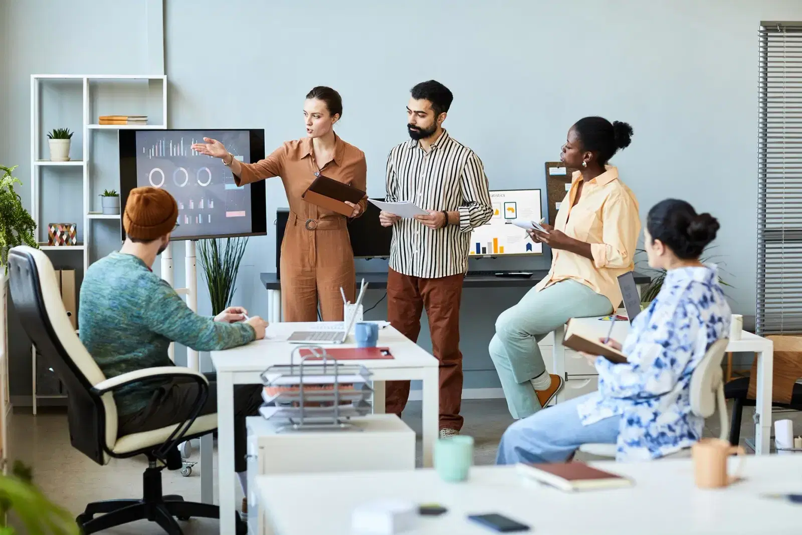 Four colleagues gathered around a desk in an office, looking at a chart together