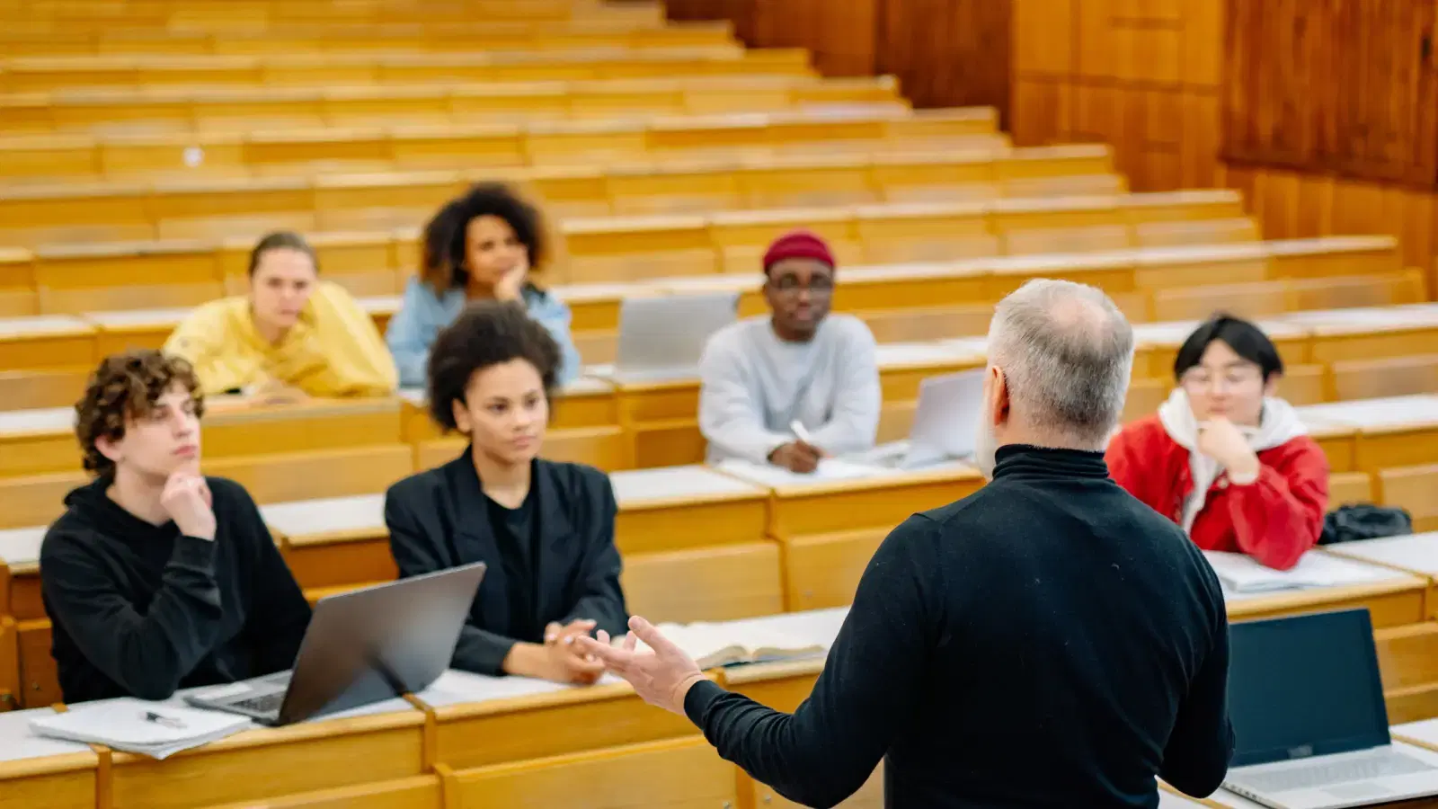 A speaker addressing a full lecture hall from the front