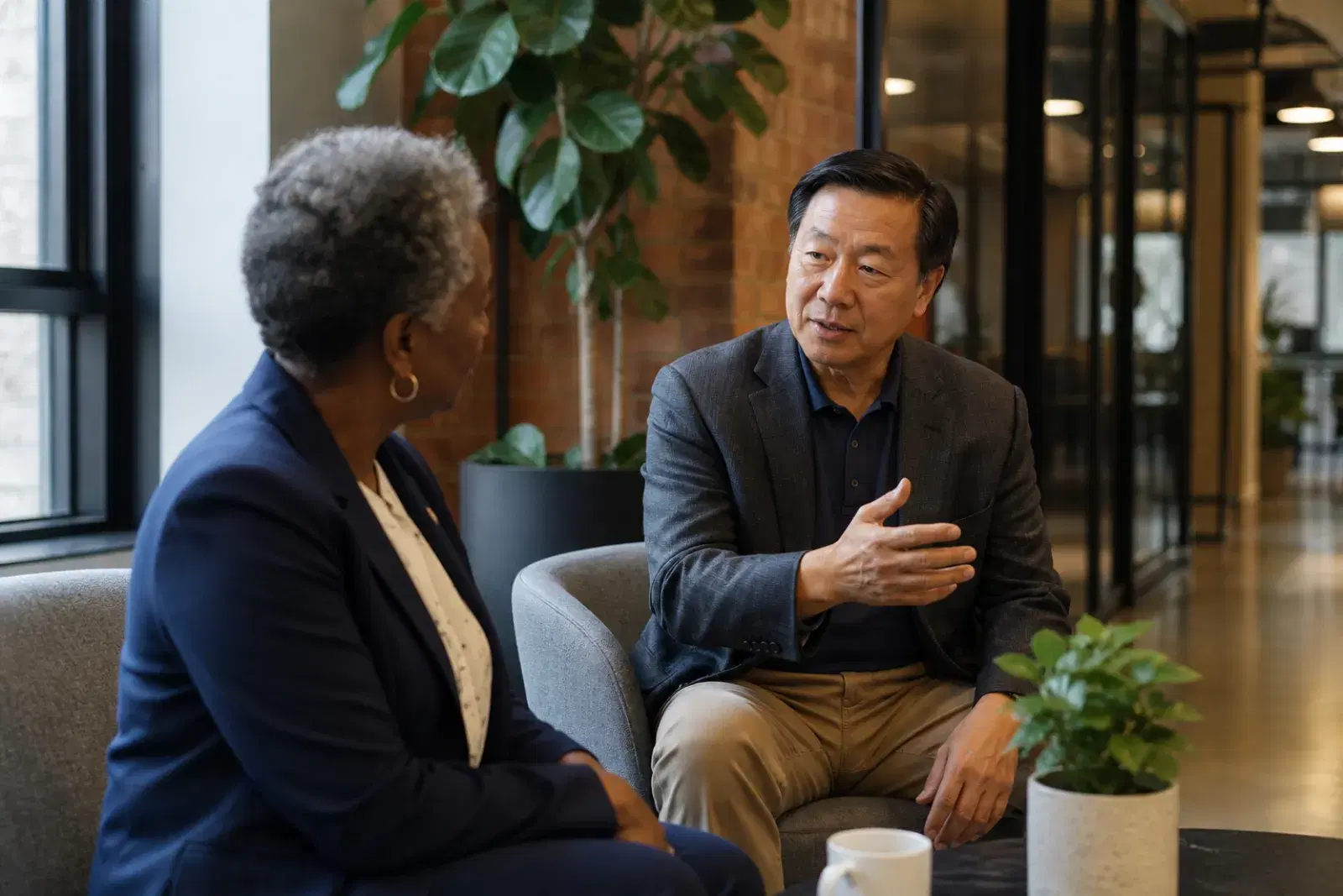 Two colleagues in an informal side conversation in a bright office breakout area.