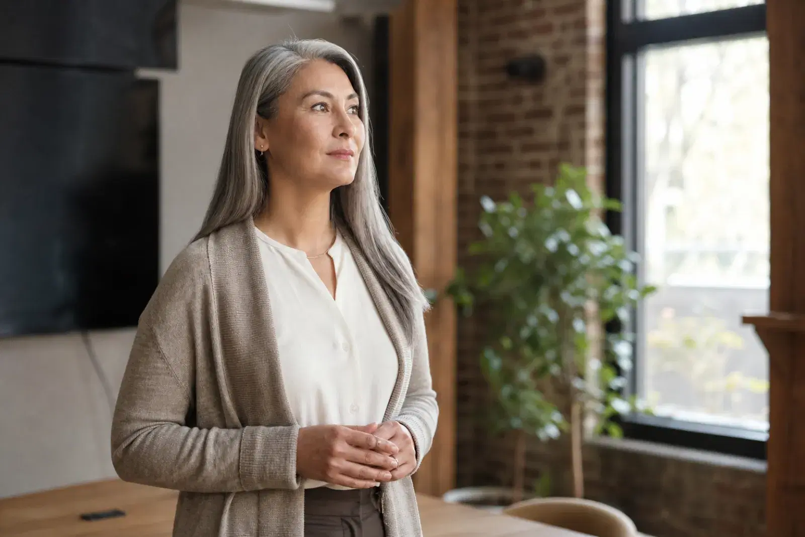 A person pausing to take a steadying breath in a quiet sunlit room before standing up to speak.