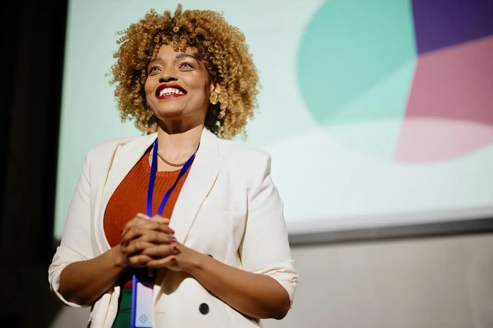 Young woman smiling on stage. Learn How to Speak with Confidence with Partners in Communication Coaching and Laurie Schloff.